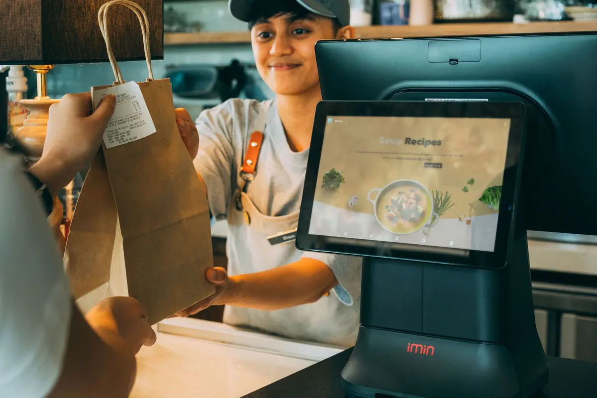 Commerçante derrière son comptoir avec un terminal de caisse compact